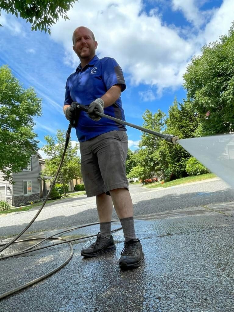 Worker pressure washing a concrete driveway