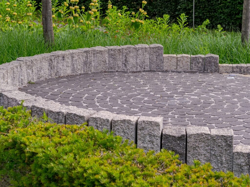 Clean paver patio with stone wall and greenery