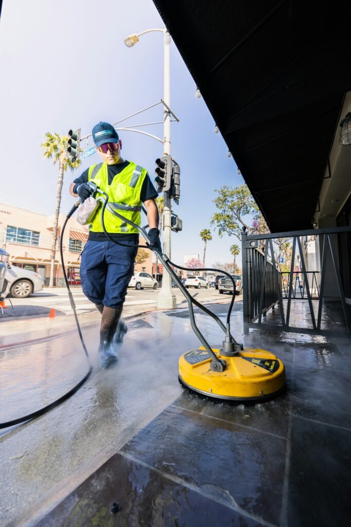 Worker cleaning a paved surface with a pressure washer